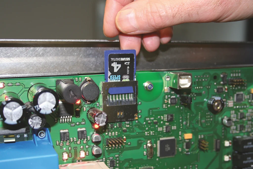 Hand steckt SD-Karte in die Platine des DISCHER Datenloggers